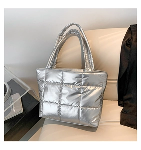 Close-up of a silver quilted tote bag with a metallic finish on a soft beige chair