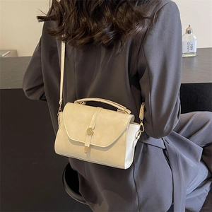 Sac à main bandoulière crème minimaliste avec détails dorés porté sur un blazer chic