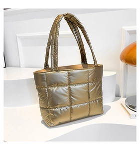 Detail of champagne gold quilted tote bag with metallic puffer texture and dual handles