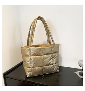 Detail of champagne gold quilted tote bag with metallic fiber texture and wide handle