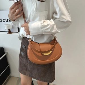 Minimalist caramel brown leather half-moon saddle bag with gold metal ring accent