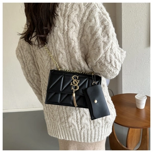 Détail du sac matelassé noir avec logo SS doré, pompon et mini porte-monnaie