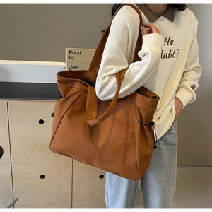 Detail of a brown canvas tote bag featuring side drawstrings and adjustable shoulder strap