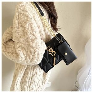 Détail du sac à bandoulière noir matelassé avec chaîne dorée et mini porte-monnaie