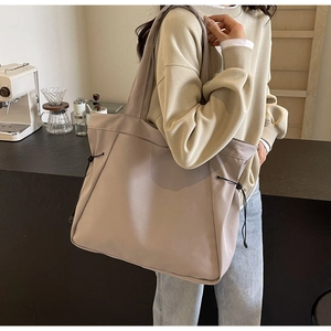 Close-up of light gray large capacity tote bag with adjustable side drawstring detail