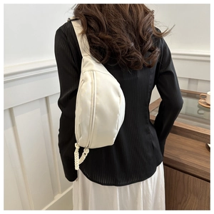 Close-up of cream half-moon chest bag with woven rope zipper detail on model's back