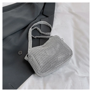Close-up of sparkling silver rhinestone square shoulder bag on grey suit jacket
