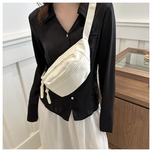 Detail of beige crossbody bag featuring woven rope zipper pulls and adjustable strap