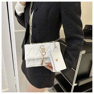 Détail du sac matelassé blanc avec logo SS doré, pompon et bandoulière en chaîne dorée