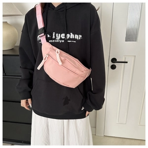 Close-up of pink nylon chest bag with woven zipper pull worn by model in casual setting