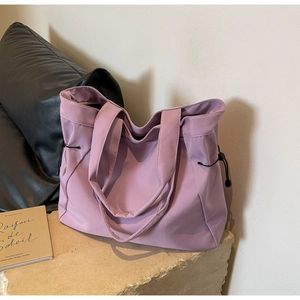 Detail view of a light purple large tote bag with side drawstring on a stone base