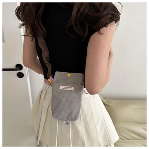 Rear view of a grey corduroy phone bag with adjustable brown strap and yellow button