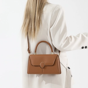 Borsa a tracolla in pelle marrone minimalista con fibbia dorata indossata da modella