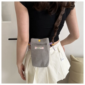 Detail of grey corduroy mobile phone bag featuring a yellow snap button and ruffled strap