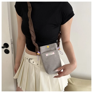 Detail of grey corduroy crossbody phone bag featuring purple drawstrings and a wide strap