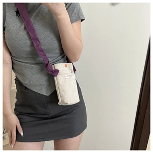 Detail of corduroy crossbody phone bag with purple strap and About That Monday label