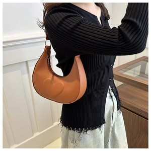 Close-up of heart-shaped embossed texture on brown crescent-shaped shoulder bag