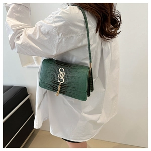 Detail of dark green crocodile texture shoulder bag with gold SS logo and tassel