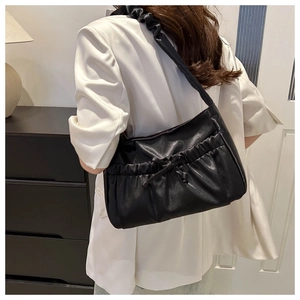 Side view of black pleated cloud bag with drawstring bow detail worn by model