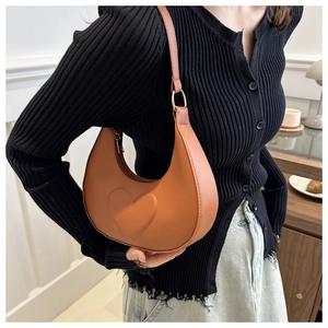 Detail of caramel crescent underarm bag with embossed 3D heart design and gold zipper