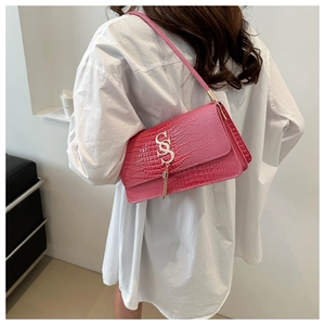 Pink crocodile pattern shoulder bag with gold SS logo and tassel detail worn by model