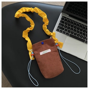Detailed macro view of corduroy phone bag with yellow pleated strap and blue drawstring