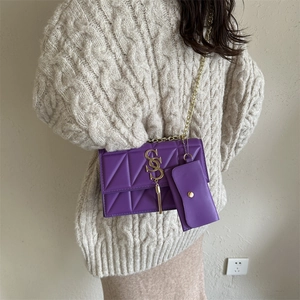 Sac bandoulière violet matelassé avec chaîne dorée porté par un mannequin en pull