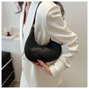 Detail of black crescent hobo bag with 3D heart design worn with a beige blazer