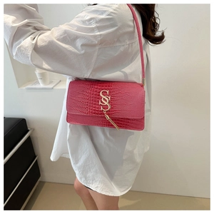Detail of rose red faux crocodile shoulder bag with gold logo on white shirt model