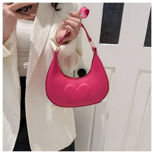 Detail of hot pink crescent bag with embossed heart pattern and gold hardware