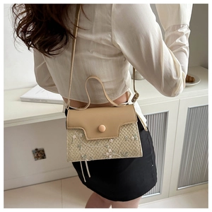 Detail of straw woven crossbody bag with white floral embroidery and leather flap