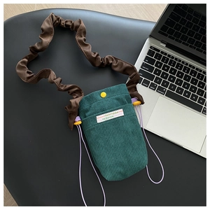 Green corduroy phone bag with brown scrunchie strap and yellow snap button detail