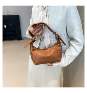 Detail einer braunen Leder-Schultertasche mit Silberschnallen und Reißverschluss