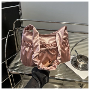 Detailed shot of pink satin handbag with ruffles and a bow against metallic shelf