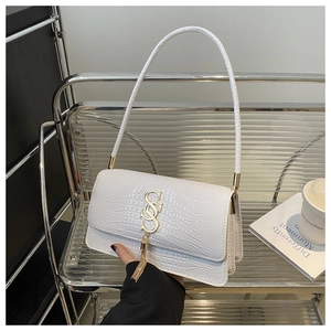 Detail of white crocodile pattern shoulder bag with gold metal logo and tassel charm