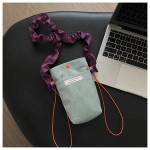 Detail of mint green corduroy crossbody phone bag with purple pleated strap and orange buckle