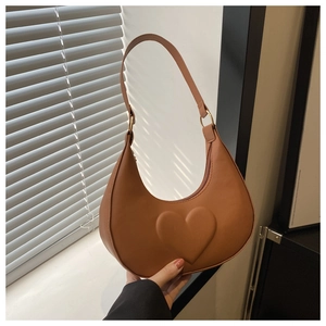 Close-up of caramel crescent bag with embossed heart detail and matte leather texture