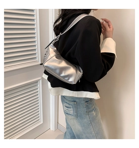 Detail der silbernen Metallic-Hobo-Tasche mit sichelförmigem Design und Logo-Plakette