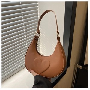 Close-up of brown crescent hobo bag featuring 3D heart-shaped relief and gold hardware