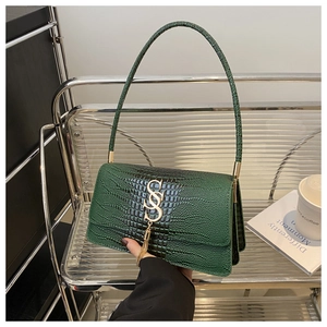 Detail of green crocodile texture leather shoulder bag with golden tassel logo