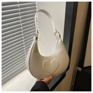 Detail of white leather hobo bag featuring 3D heart embossing and gold ring hardware