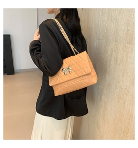 Détail du sac matelassé rose orangé avec nœud argenté porté en bandoulière par un mannequin