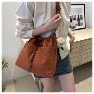 Dettaglio della borsa in nylon rosso ruggine con ciondolo di peluche su una modella