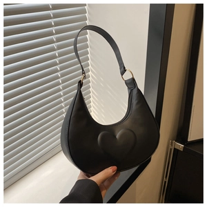 Detail of black crescent hobo bag featuring 3D embossed heart and gold metal rings