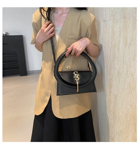 Detail der schwarzen Lederhandtasche mit Rundgriff und goldenem S-förmigem Anhänger