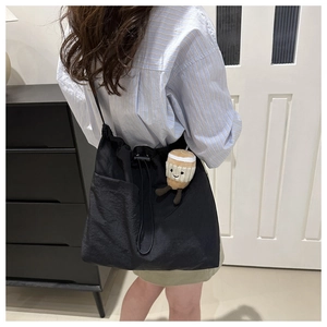Dettaglio della borsa tote nera in nylon con coulisse e ciondolo di peluche decorativo