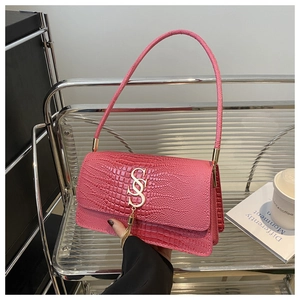 Detailed view of pink embossed leather shoulder bag with gold S logo and tassel detail