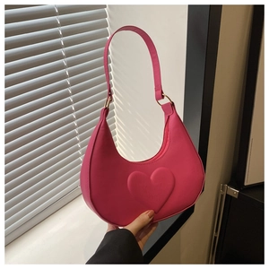 Detail of rose red crescent bag featuring embossed heart patterns and gold hardware