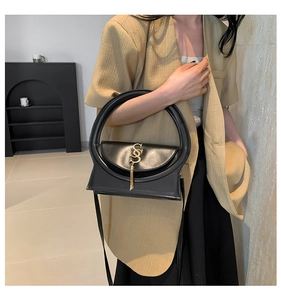 Detail der schwarzen Lederhandtasche mit großem Rundgriff und goldenem S-Quastenanhänger