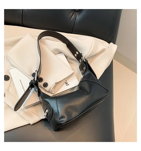 Detail einer schwarzen Lederschultertasche mit dekorativen Silbernieten und Metallschnalle